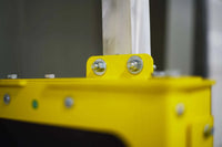 Close-up of a yellow metal object with screws on a blurred background