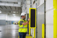 Person in a warehouse wearing a safety vest and hard hat, interacting RFID U-Bolt pole mount for EasyPort Flex antenna installation